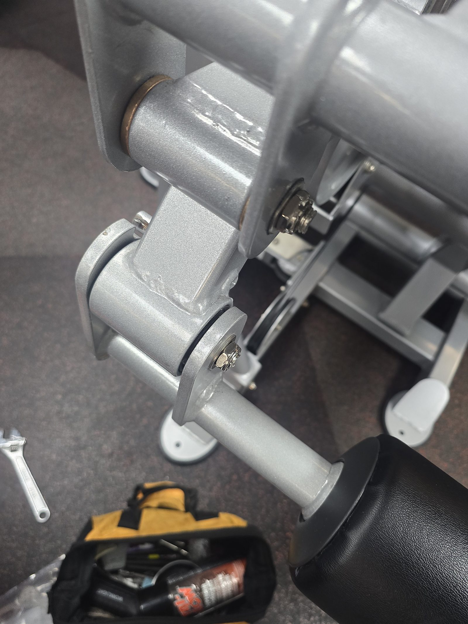 Strength machine pivot mid-repair with wrench and tool bag